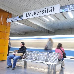 Personen warten an der U-Bahn Haltestelle der LMU.