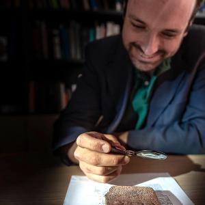 Professor Enrique Jiménez sitzt am Tisch und betrachtet einen Gegenstand in der Hand.